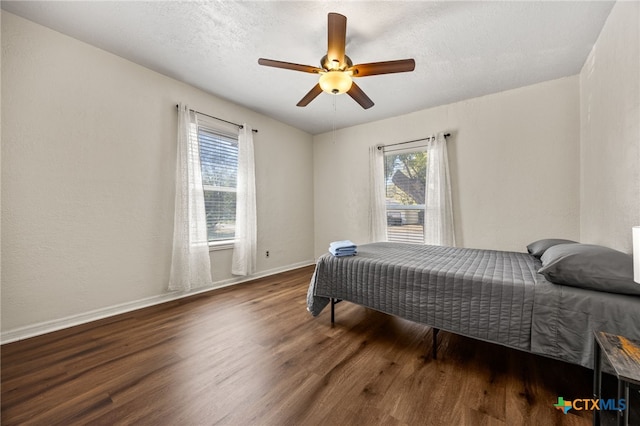 bedroom with dark wood-type flooring, multiple windows, and ceiling fan