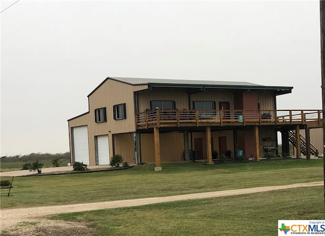 rear view of house featuring a garage, a wooden deck, and a lawn