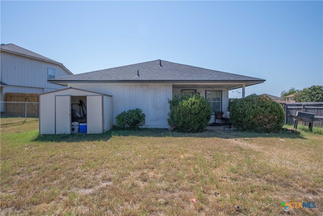 back of property featuring a lawn and a storage unit