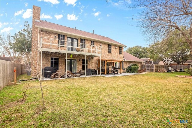 back of house featuring a fenced backyard, a chimney, a yard, a patio area, and brick siding