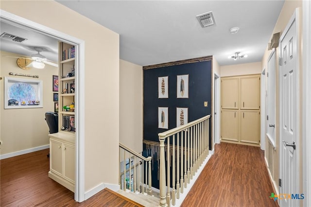 hall featuring visible vents, baseboards, and wood finished floors