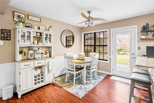 dining area featuring dark wood-style floors, a wainscoted wall, and ceiling fan