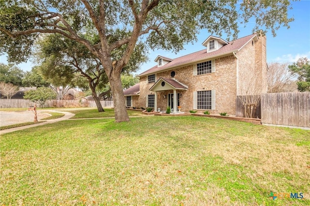 view of front of property featuring brick siding, fence, and a front yard