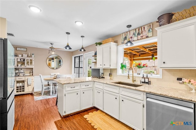 kitchen featuring pendant lighting, a peninsula, a sink, and white cabinets