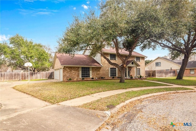 traditional-style home featuring concrete driveway, an attached garage, fence, a front lawn, and brick siding