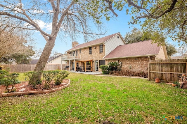 back of property featuring a patio, a fenced backyard, a chimney, a yard, and brick siding