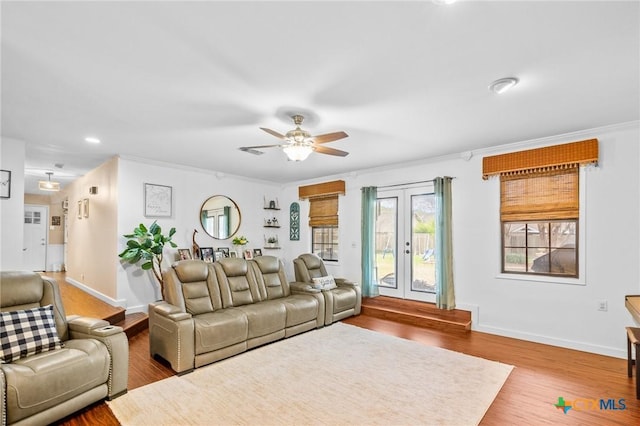 living area with crown molding, baseboards, wood finished floors, and french doors