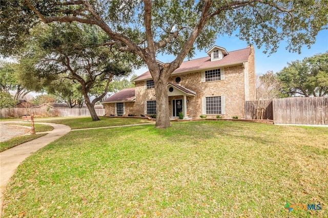 view of front of home featuring fence, a front lawn, and brick siding