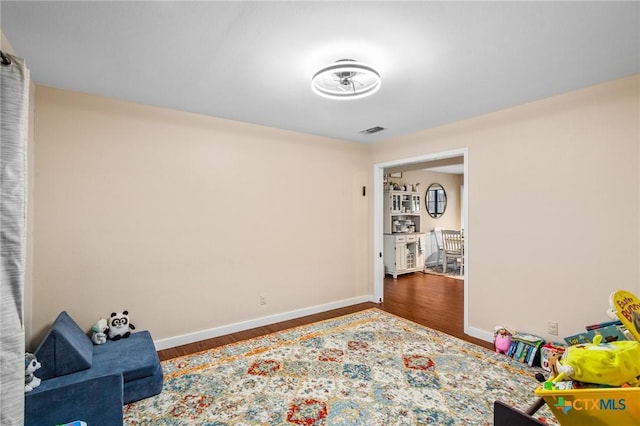 rec room with wood finished floors, visible vents, and baseboards