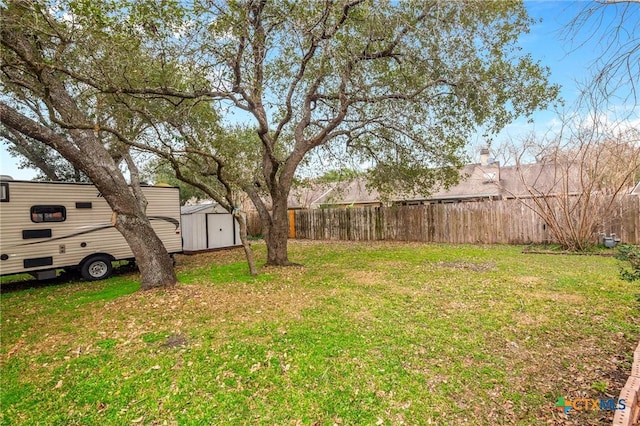 view of yard with a storage shed, an outdoor structure, and fence