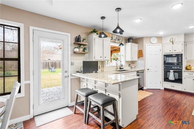 kitchen featuring a breakfast bar, white cabinetry, black appliances, and open shelves