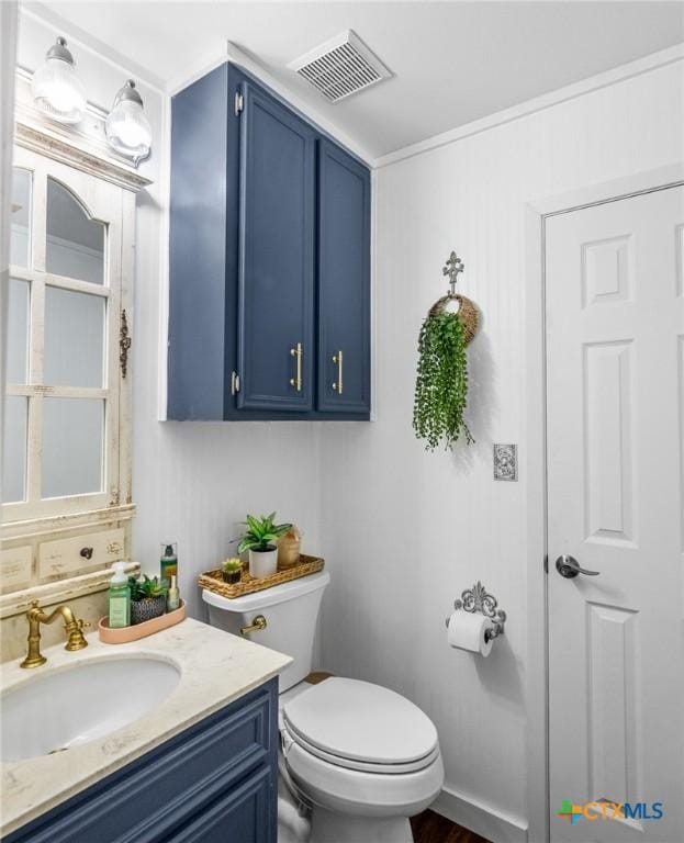 bathroom with toilet, visible vents, and vanity