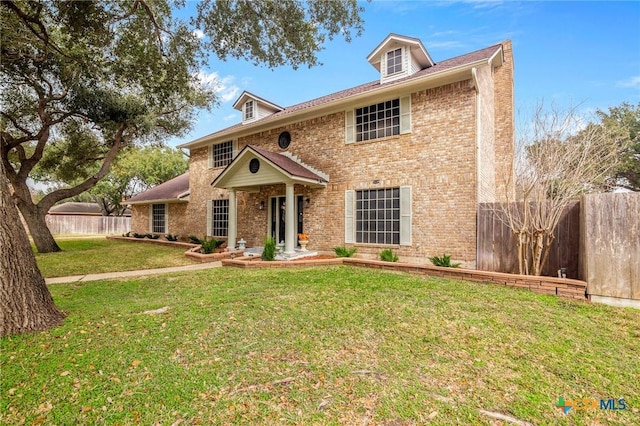 view of front of property with brick siding, a front lawn, and fence