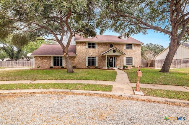 view of front of property featuring a front yard, brick siding, and fence