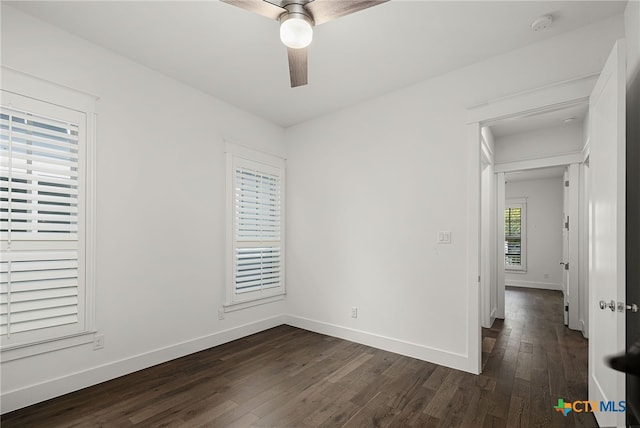 unfurnished room featuring a ceiling fan, baseboards, and dark wood-style flooring