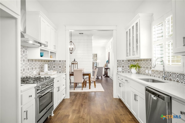 kitchen with a sink, stainless steel appliances, light countertops, white cabinetry, and wall chimney exhaust hood