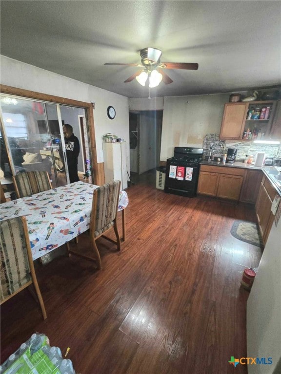 kitchen featuring gas stove, decorative backsplash, ceiling fan, and dark hardwood / wood-style flooring