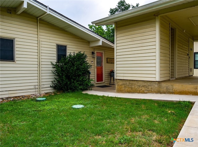 doorway to property with a patio area and a yard