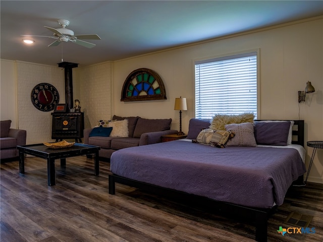 bedroom featuring dark wood-type flooring, ornamental molding, a wood stove, and ceiling fan