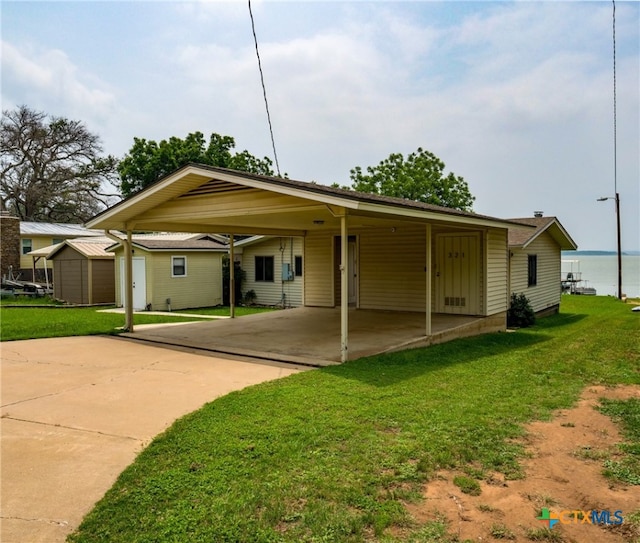 back of house featuring a shed, a lawn, a carport, and a water view