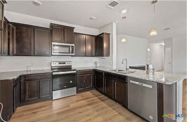 5836 Copano Rd, Belton, TX 76513 - kitchen with stainless steel appliances, a peninsula, dark brown cabinetry, light stone countertops, and light wood-style flooring