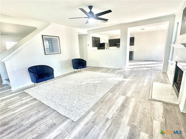 living area featuring ceiling fan, light hardwood / wood-style floors, and ornamental molding