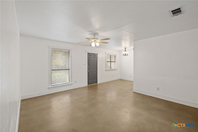 empty room featuring a textured ceiling and ceiling fan with notable chandelier