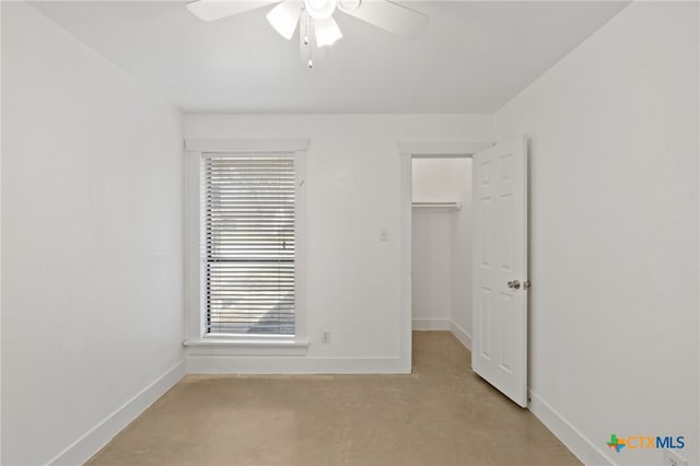 unfurnished bedroom with a walk in closet, ceiling fan, a closet, and light colored carpet