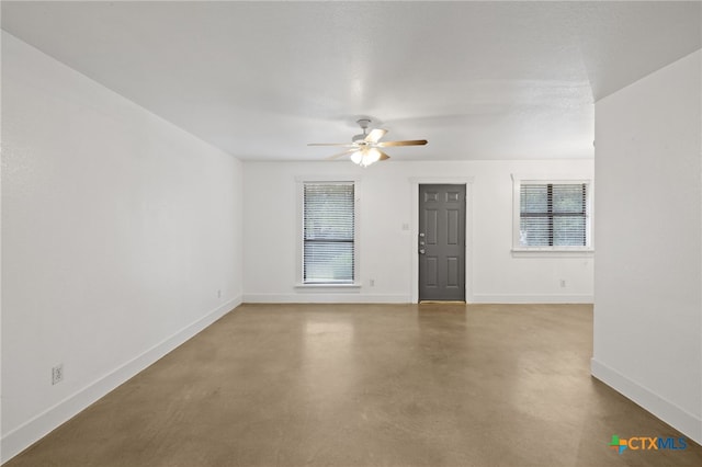 unfurnished room with ceiling fan and concrete floors