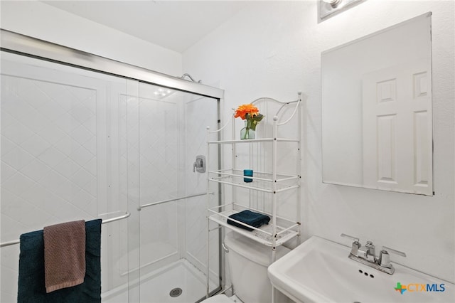 bathroom with sink, an enclosed shower, and toilet