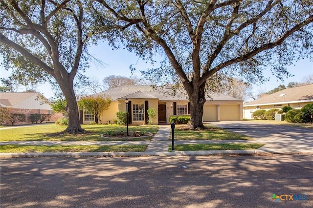 ranch-style house with concrete driveway, a garage, and a front lawn