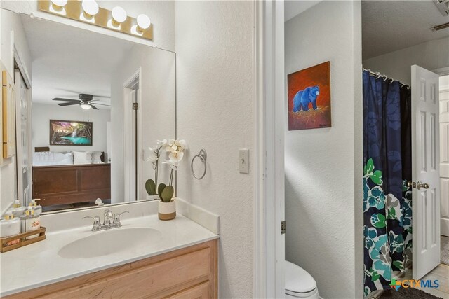 514 Duncan Dr, San Marcos, TX 78666 - ensuite bathroom with vanity, a ceiling fan, a textured wall, toilet, and curtained shower