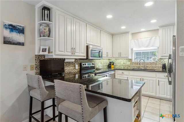 514 Duncan Dr, San Marcos, TX 78666 - kitchen featuring appliances with stainless steel finishes, a sink, open shelves, a peninsula, and backsplash