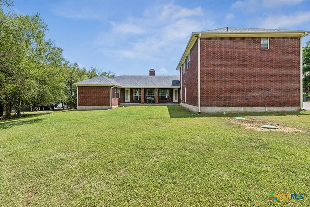 514 Duncan Dr, San Marcos, TX 78666 - rear view of house with brick siding and a lawn