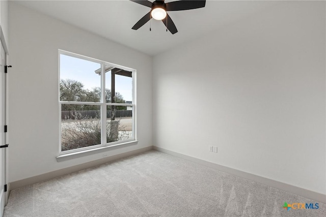 carpeted spare room featuring baseboards and a ceiling fan