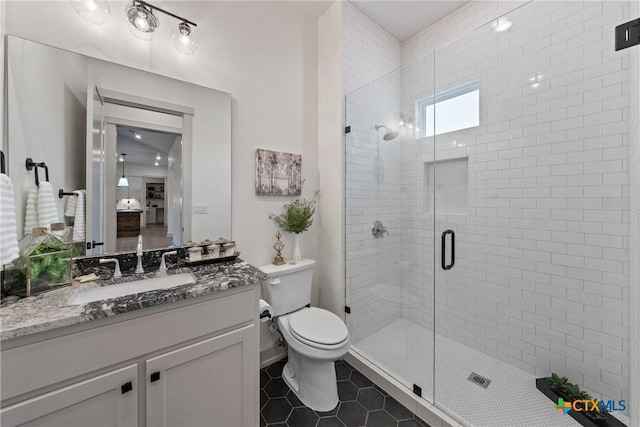 full bathroom featuring a stall shower, vanity, toilet, and tile patterned floors