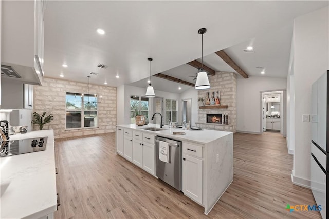 kitchen with lofted ceiling with beams, open floor plan, black electric stovetop, a stone fireplace, and stainless steel dishwasher