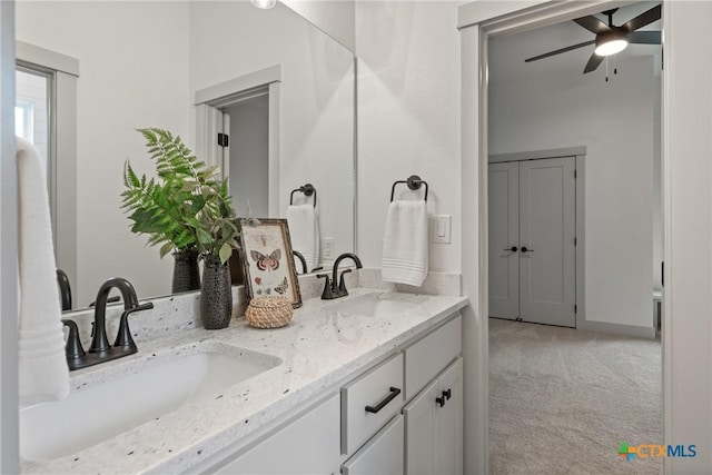 bathroom with a ceiling fan, a sink, baseboards, and double vanity