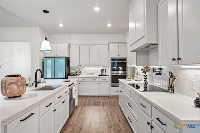 kitchen with appliances with stainless steel finishes, a sink, and white cabinetry