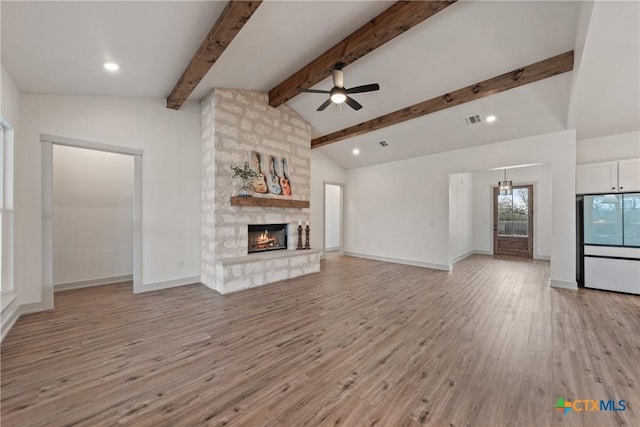 unfurnished living room featuring lofted ceiling with beams, ceiling fan, a fireplace, visible vents, and light wood-style floors