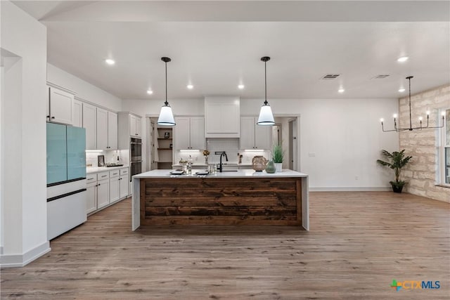 kitchen featuring light wood-type flooring, decorative backsplash, white refrigerator, and light countertops