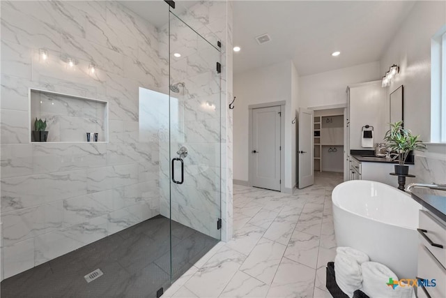 bathroom featuring recessed lighting, a freestanding bath, marble finish floor, a marble finish shower, and a walk in closet