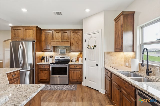 304 Campo Colinas Dr, Bertram, TX 78605 - kitchen with stainless steel appliances, premium range hood, light wood-style floors, backsplash, and light stone countertops