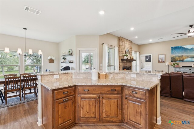 304 Campo Colinas Dr, Bertram, TX 78605 - kitchen with open floor plan, wood finished floors, a ceiling fan, light stone counters, and brown cabinetry