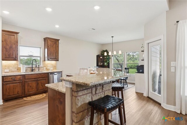 304 Campo Colinas Dr, Bertram, TX 78605 - kitchen with stainless steel dishwasher, light wood-type flooring, backsplash, a breakfast bar, and recessed lighting
