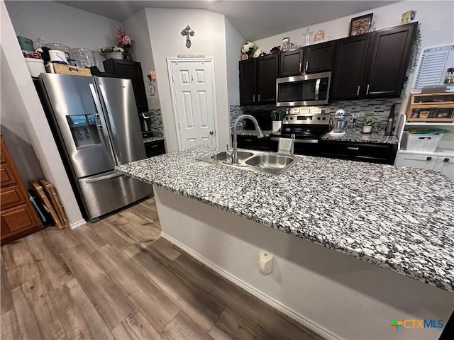 1036 Chambray Dr, Troy, TX 76579 - kitchen with appliances with stainless steel finishes, light wood-style flooring, backsplash, light stone countertops, and dark cabinetry