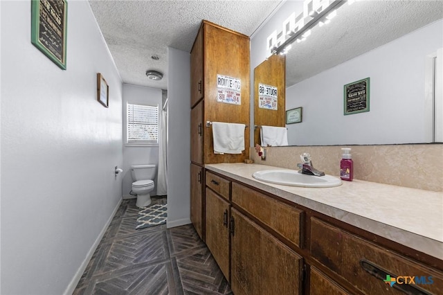 bathroom featuring parquet flooring, vanity, toilet, and a textured ceiling