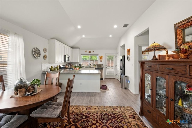 128 Riverhill Dr, Georgetown, TX 78628 - kitchen featuring appliances with stainless steel finishes, a peninsula, white cabinetry, light wood-style floors, and lofted ceiling