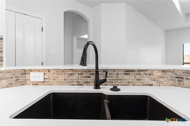 interior details with tasteful backsplash, sink, and white cabinets