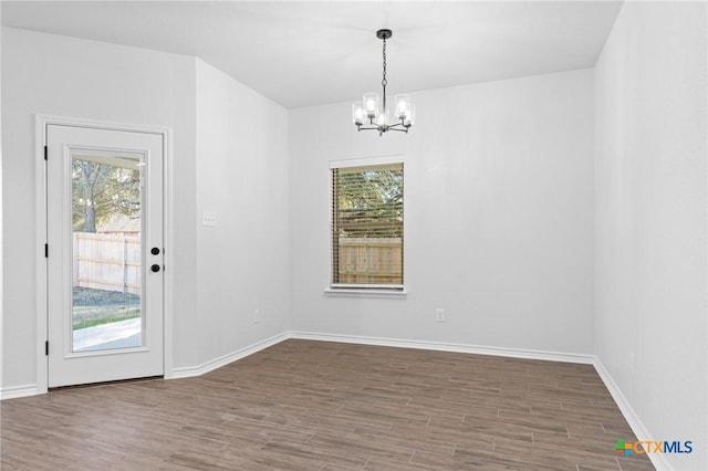 unfurnished dining area with an inviting chandelier, wood-type flooring, and plenty of natural light